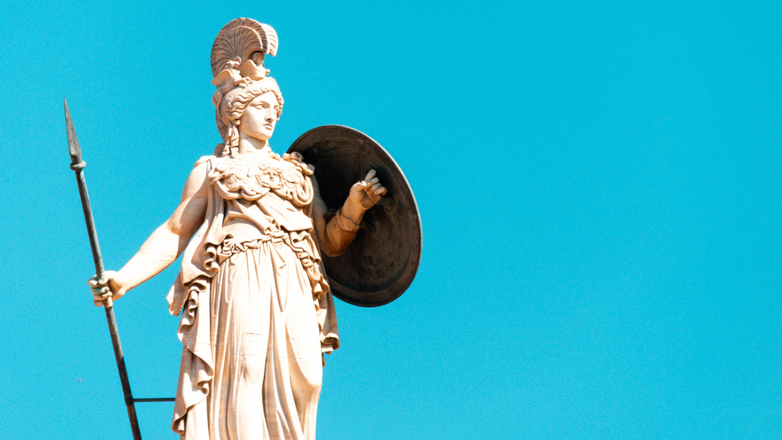 A photo of a statue of Athena with her shield and spear and Aegis on a blue sky background.