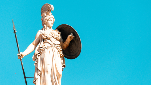 A photo of a statue of Athena with her shield and spear and Aegis on a blue sky background.