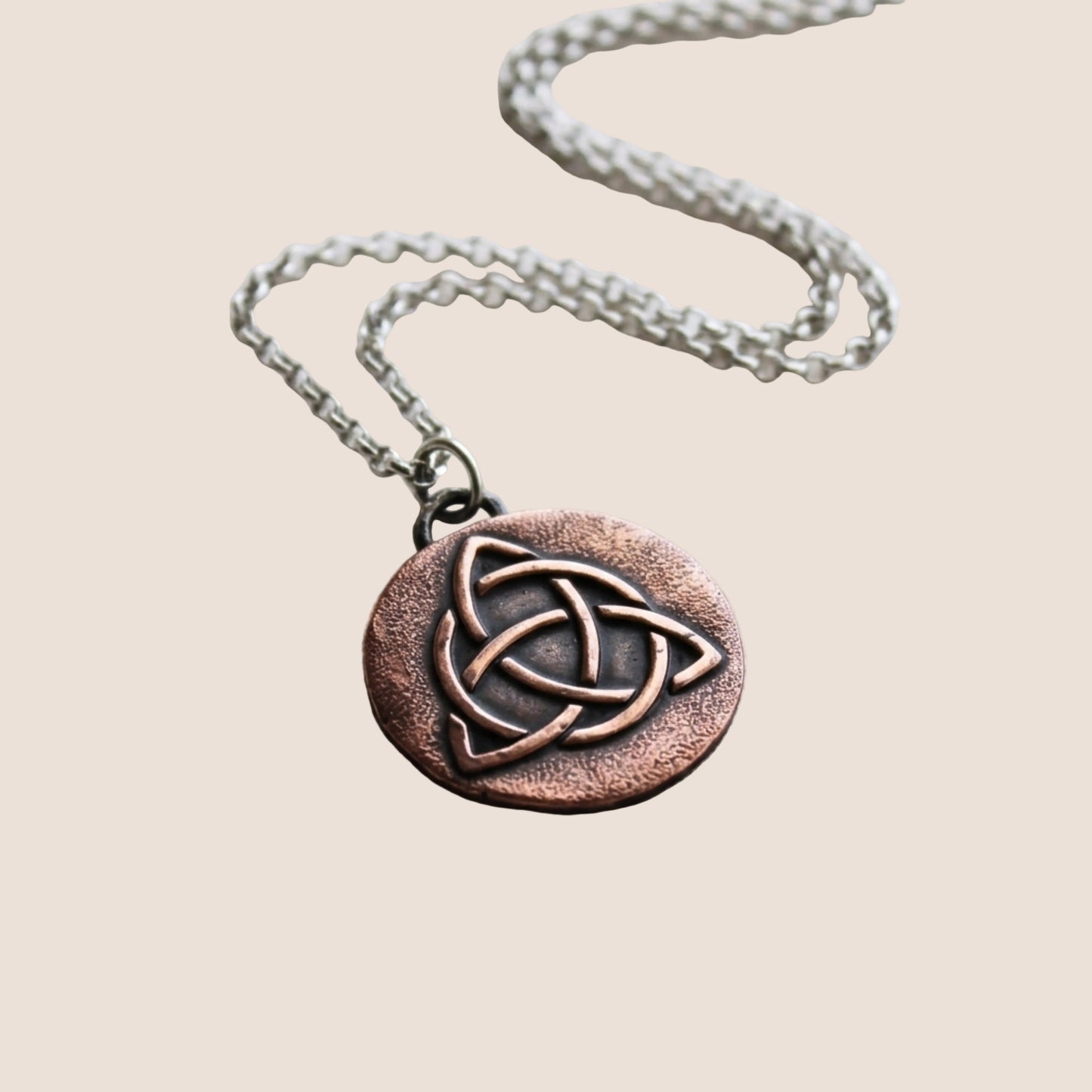 photo of 1" copper medal with impression of Celtic triquetra knot with silver bail and chain